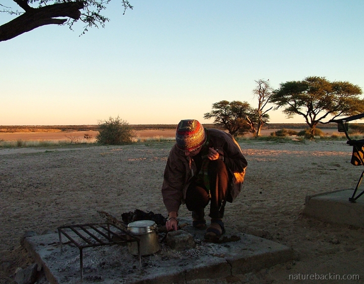 Rekindling the previous night's campfire, Mabuasehube, Botswana
